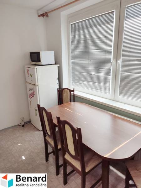 Dining area with a wooden table and chairs in a 2-room apartment.