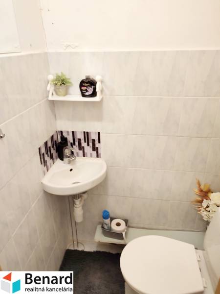 A small bathroom in a two-room apartment with a sink, toilet, and decorations.