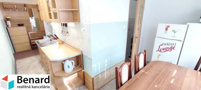 A kitchen connected to a dining table in a 2-room apartment, equipped with basic appliances.