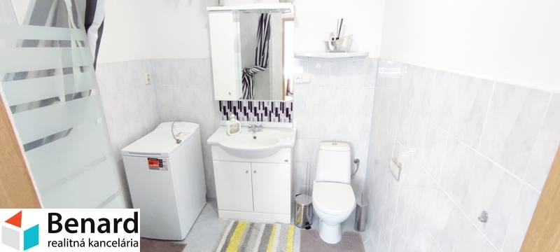 Bathroom in a 2-room apartment with a washing machine, sink, and toilet, tiles in light shades.
