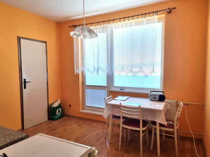 Interior of a 2-room apartment with a dining table, chairs, and a large window.
