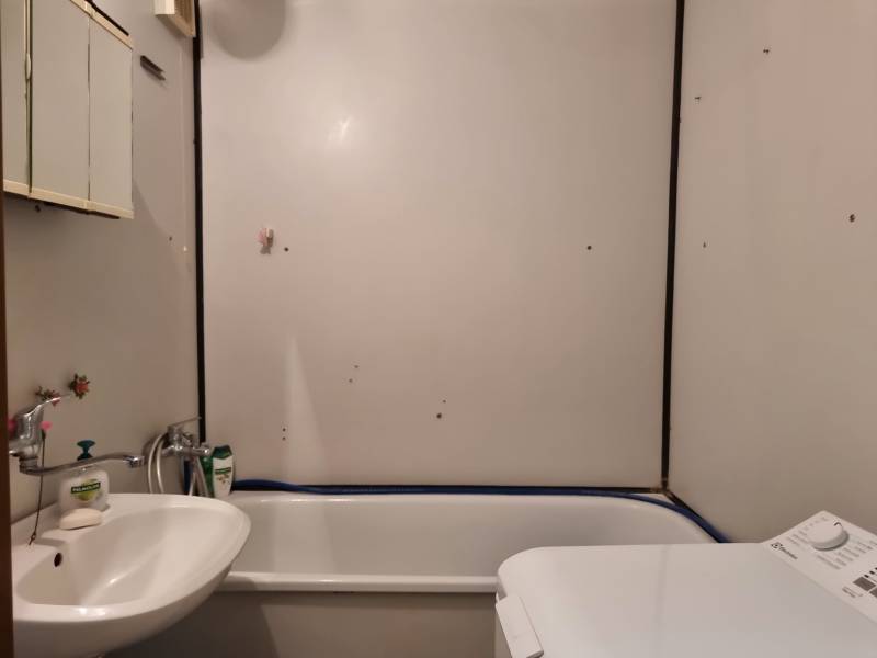 Bathroom in a 2-room apartment with a bathtub, sink, and washing machine.