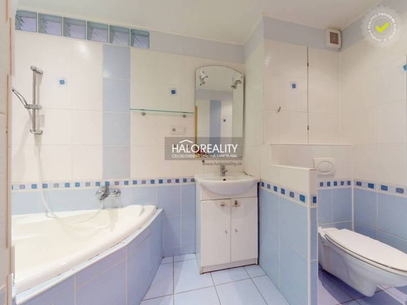A bathroom in a 3-room apartment with light blue tiles, a bathtub, and a sink.