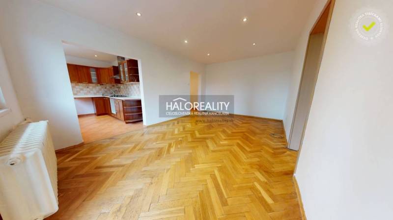 A spacious living area in a 3-room apartment with parquet flooring and a kitchen.