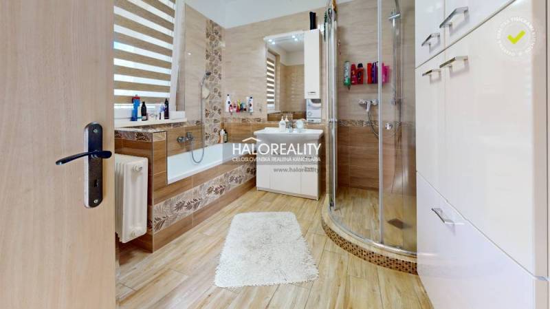 A bathroom in a family house with a bathtub, shower, and sink, warm wood tones.