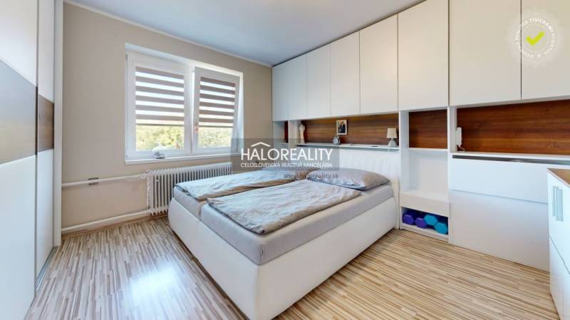 A bedroom in a family house with a large bed, built-in wardrobes, and a window.