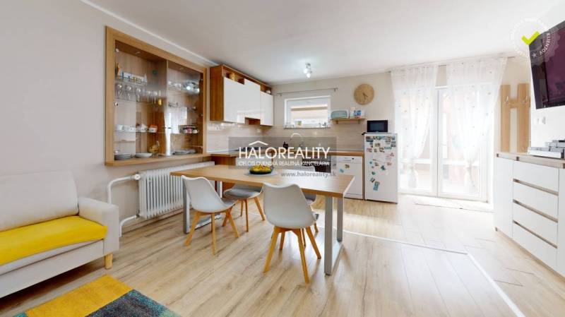 Interior of a family house with a dining table, kitchen, and shelves for dishes.