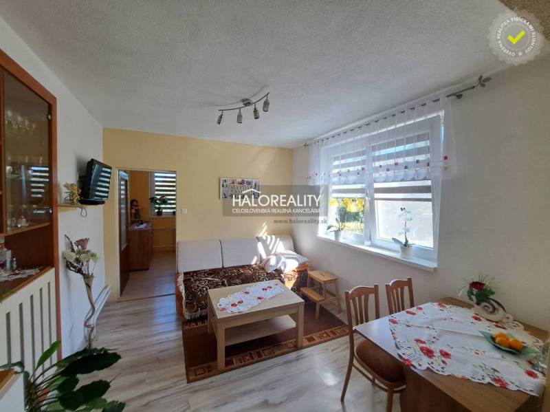 Living room in a family house with light curtains, a wooden table, and a sofa.