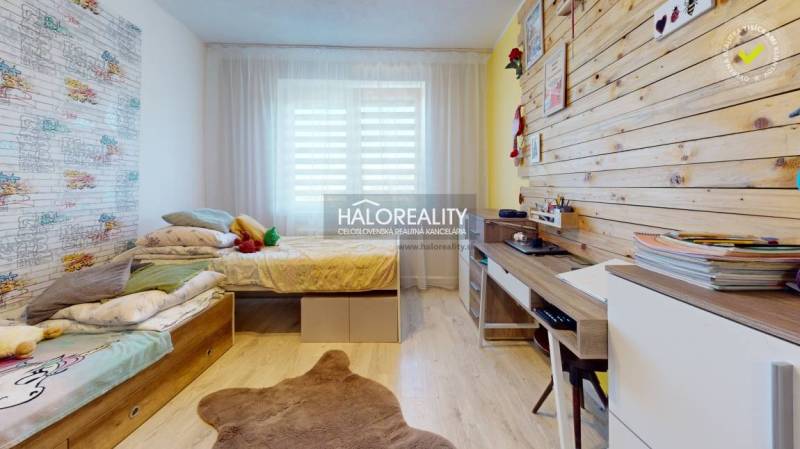 Children's room in a family house with a wooden wall, bed, and desk.