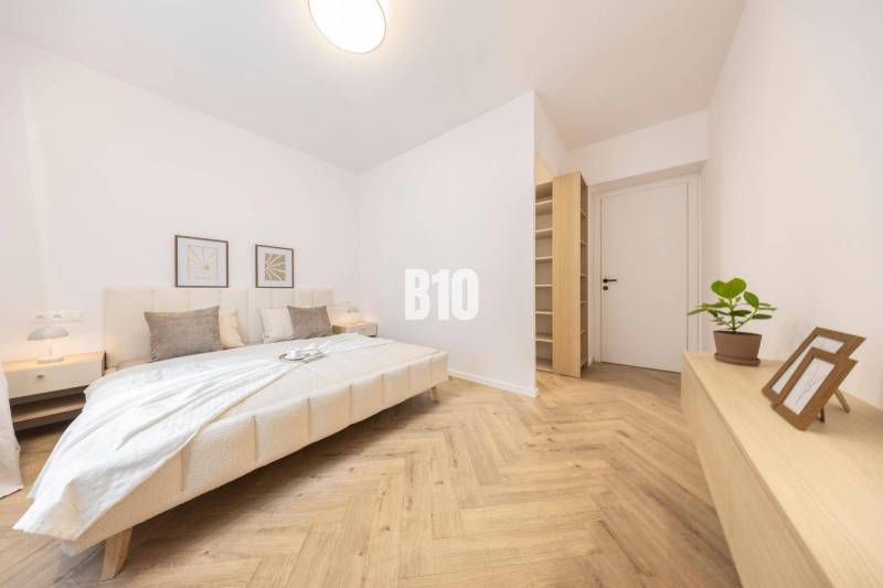 Bedroom in a 3-room apartment with a double bed, light walls, and wooden flooring.