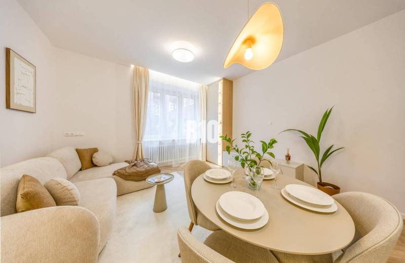 The living room in a 3-room apartment on Benediktiho Street, bright and cozy with a plant.