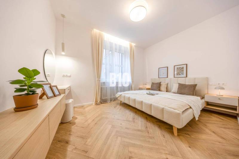 A bright bedroom with a mirror, a plant, and a comfortable bed in a 3-room apartment.