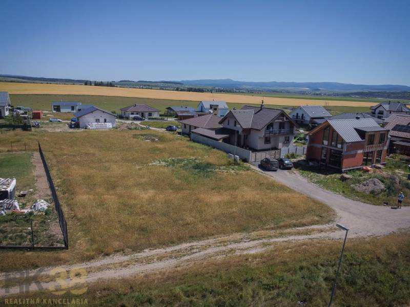 Plots - housing in Mlynica, surrounded by houses and fields, with a rural scenery.