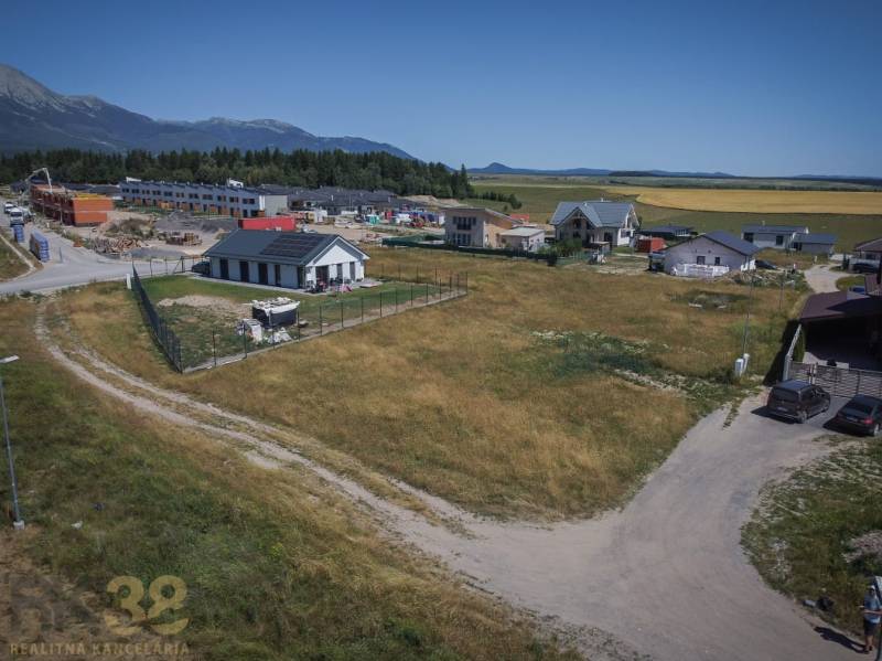 Plots - housing in Mlynica with a view of the mountains, surrounded by houses and construction activity.