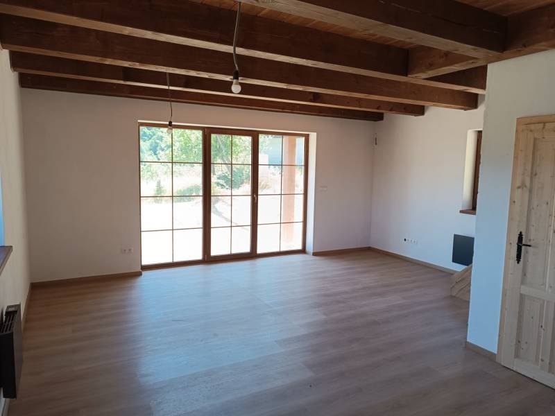 The interior of a cabin with wooden beams and large windows, bright spaces.