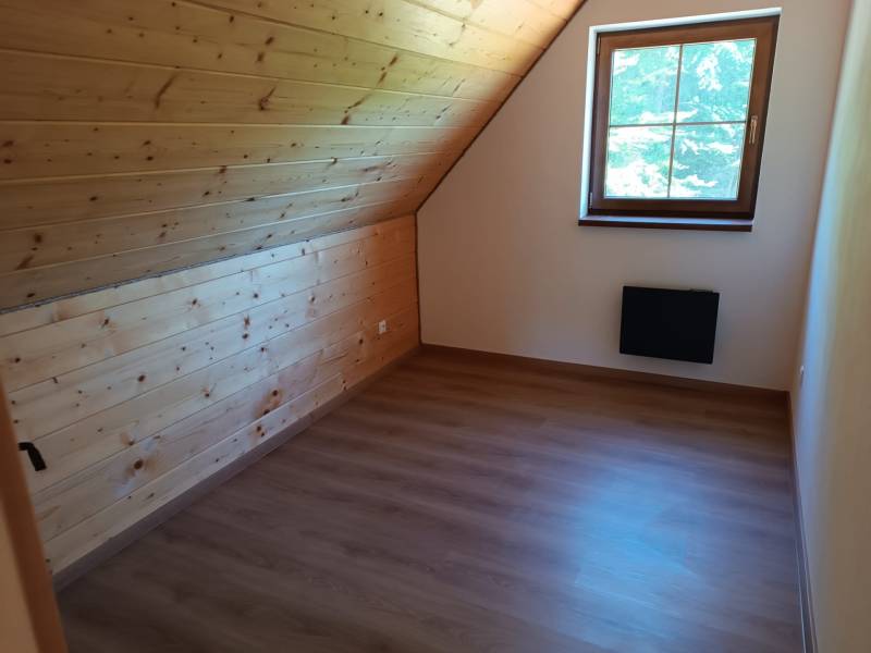 Attic room with wooden paneling and a view from the window in the cabin.