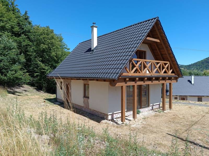 A cottage in Horné Hámre with a wooden balcony, surrounded by nature and lush greenery.