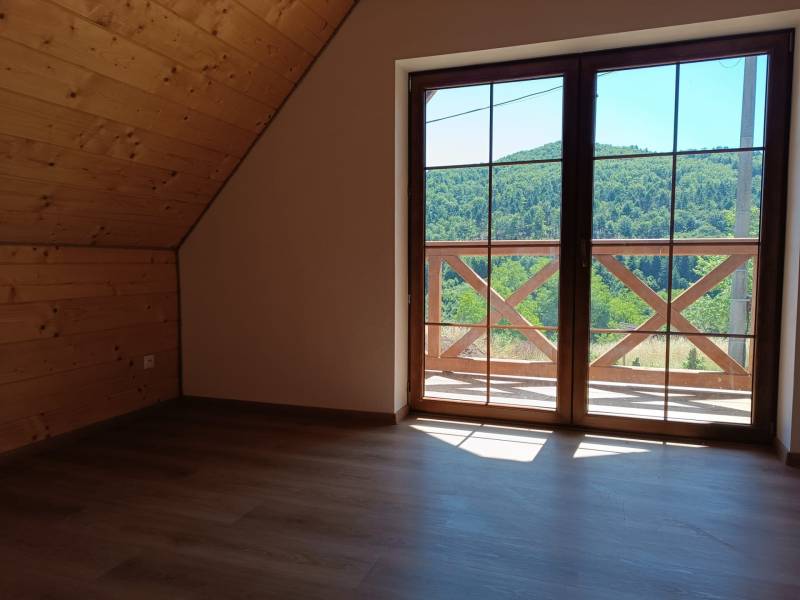 Attic of a cottage with wooden walls, view from the window to nature.