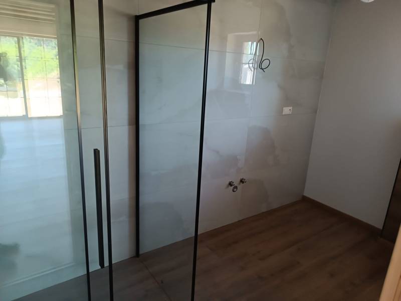 Shower enclosure with glass doors in the cabin, bright interior with wooden flooring.