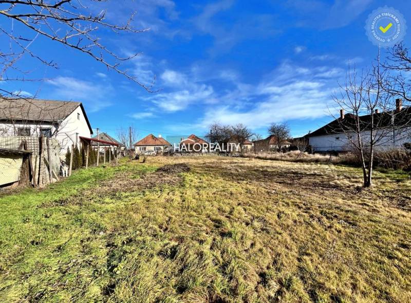 A plot for residential use in Veľké Ludince with neighboring houses and a grassy area.