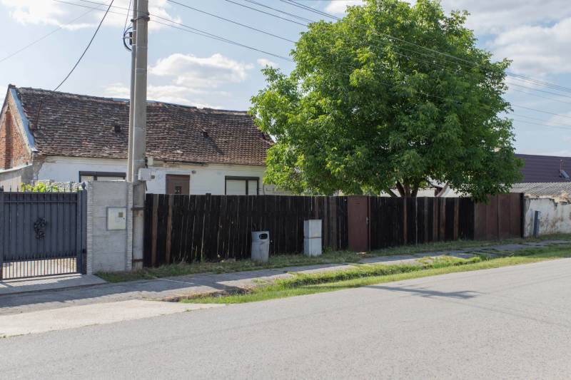 A house with a wooden fence and a tree on Športová Street in Gajary, residential plots.