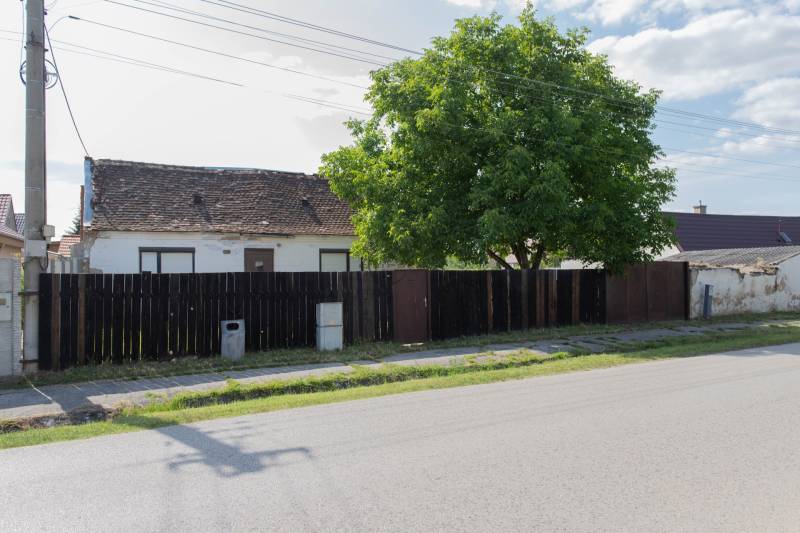 A building with an old roof on Športová Street in Gajary, surrounded by a fence. Land - residential.