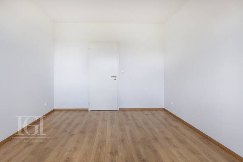 An empty room with wooden flooring and white walls in a 3-room apartment.