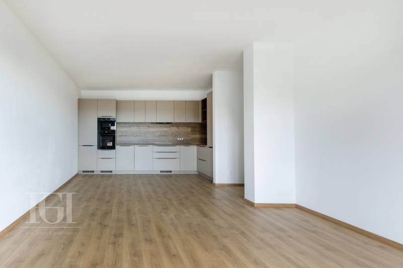 A kitchen in a 3-room apartment with wooden flooring and a light kitchen unit.