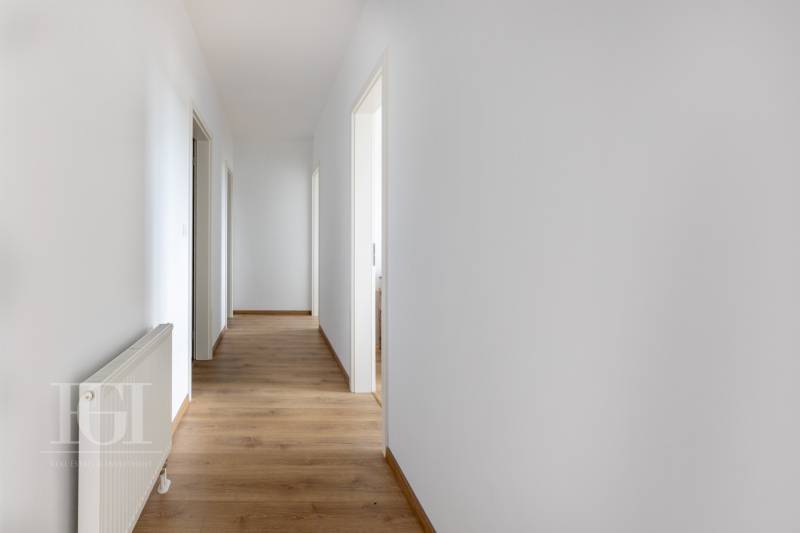 A hallway in a 3-room apartment with white walls and wooden flooring.