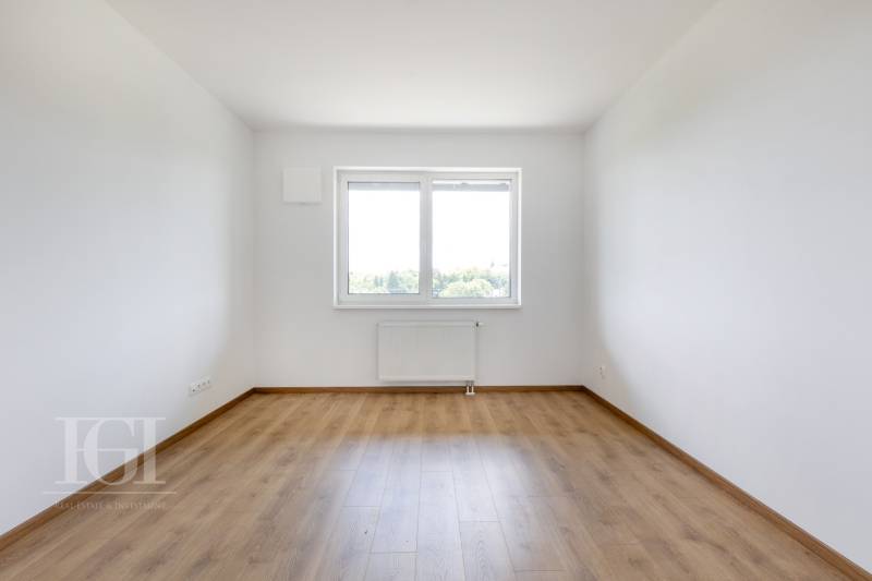 An empty room with a wooden floor and a large window in a 3-room apartment.