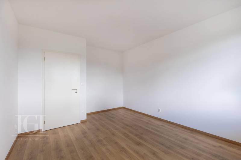 Empty room with white walls and wooden floor, suitable for a 3-room apartment.