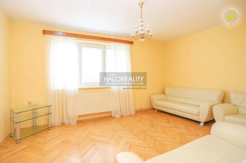 Living room in a three-room apartment with a light sofa and wooden floor.