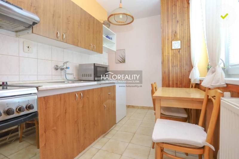 A kitchen in a 3-room apartment with wooden furniture, a stove, and a microwave oven.