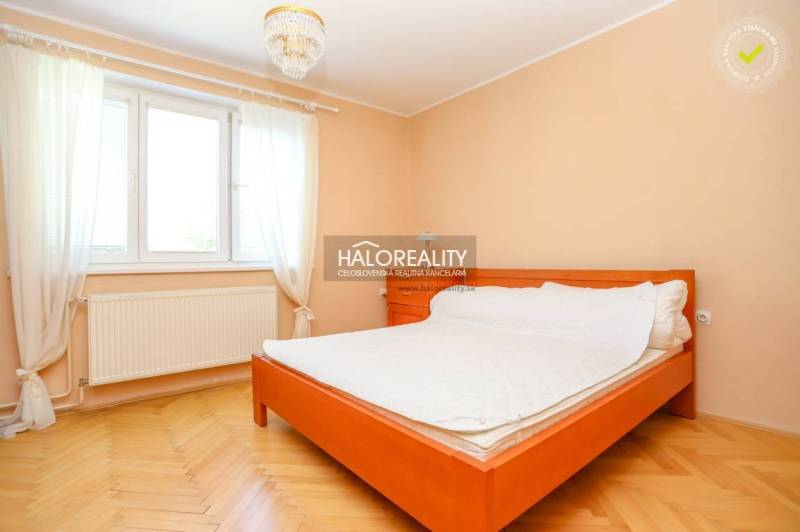 Bright bedroom in a 3-room apartment with a bed, wooden floor, and curtains.