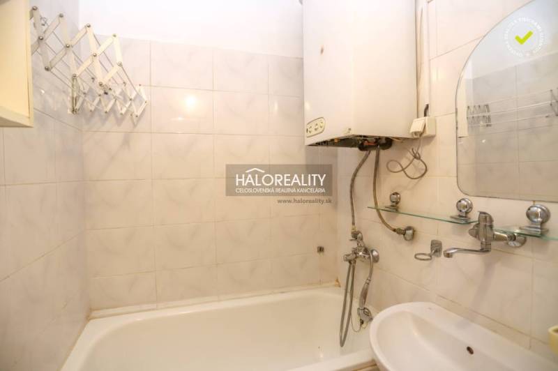 Bathroom with a bathtub and a boiler in a 3-room apartment, white tiles, sink.