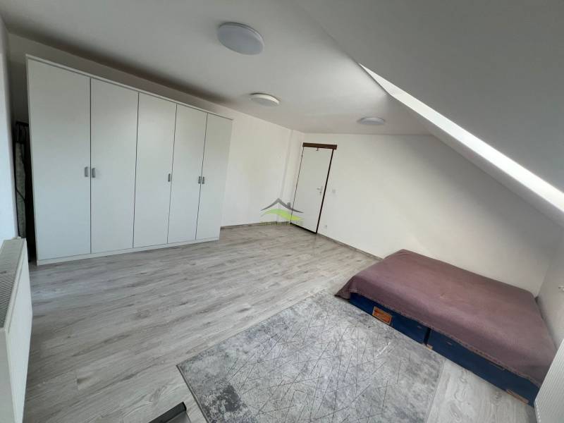 Bedroom in a family house with a sloped ceiling, a bed, opposite a large wardrobe.