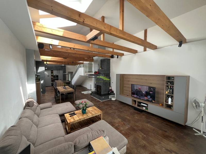 A large living space in a family house with wooden ceiling beams and a comfortable sofa.
