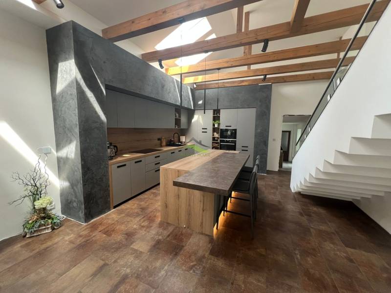 A kitchen in a family house with wooden beams and a modern kitchen island.
