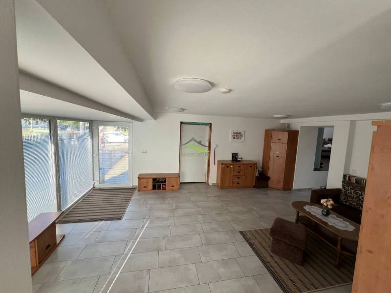 The interior of a family house with large windows, tiles, and wooden furniture.