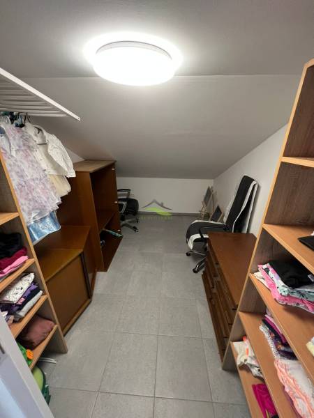 A wardrobe in a family house with shelves, a chair, and hanging clothes.