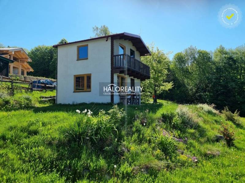 A cottage in Počúvadlo surrounded by greenery, with a balcony and a garden on a slope.