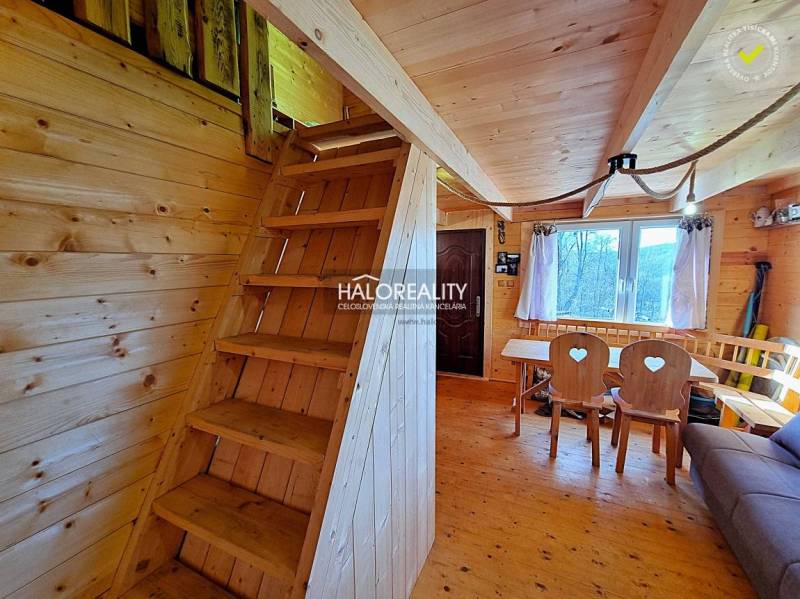 Wooden interior of a cabin with wooden stairs, a table, and comfortable seating.