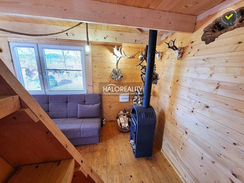 A wooden interior of a cabin with a fireplace and a sofa. The decorations made of antlers are dominant.