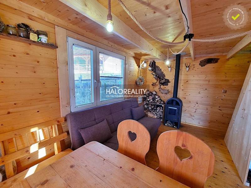 A cabin with a wooden interior, a sofa, and a stove.