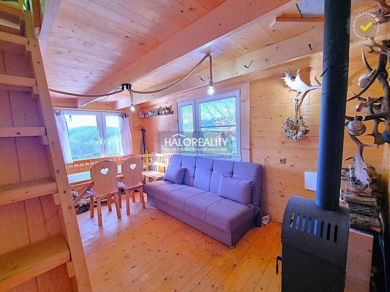The interior of a cabin with wooden furniture, a fireplace, and a view of nature.