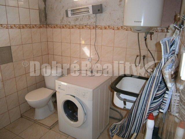Bathroom in a family house with a washing machine, toilet, and sink.