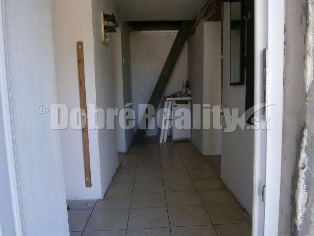 A hallway in a family house with white walls and ceramic tiles.
