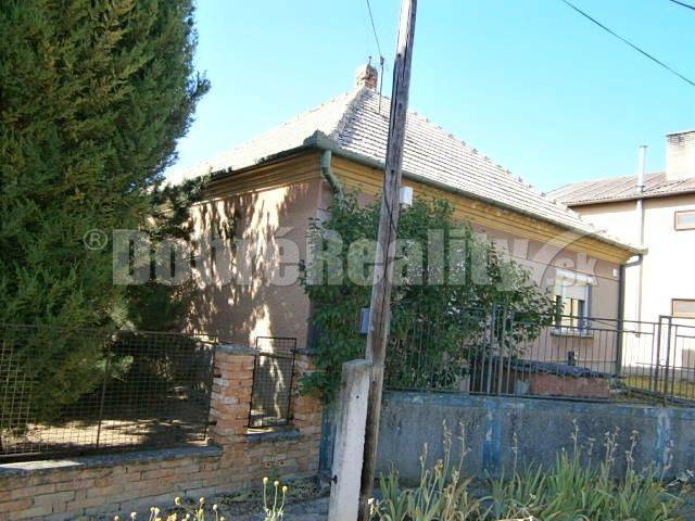 A family house in Rúbaň with an older exterior, surrounded by a fence and vegetation.