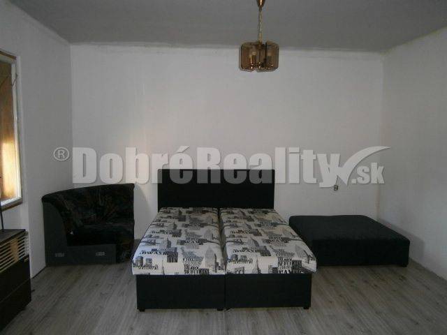 A bedroom in a family house with a bed, a sofa, and a wooden floor.