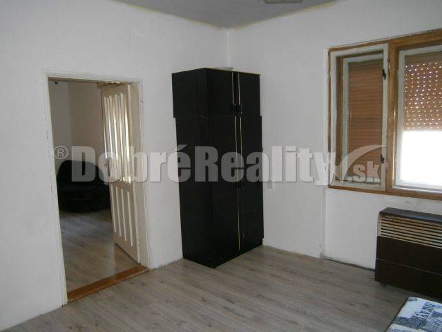 A simple interior in a family house with wooden flooring and a dark wardrobe.